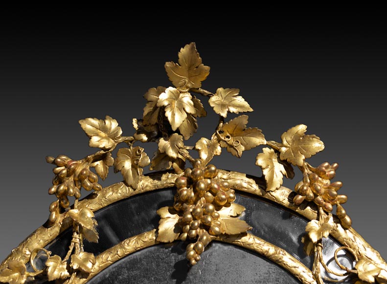 Великолепное овальное зеркало с перегородками, украшенное виноградными лозами и листьями. Великолепное овальное зеркало с перегородками, украшенное виноградными лозами и листьями.-1