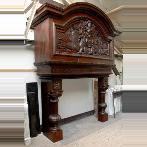 Большой старинный камин с вытяжным колпаком, изготовленный из дубового дерева.